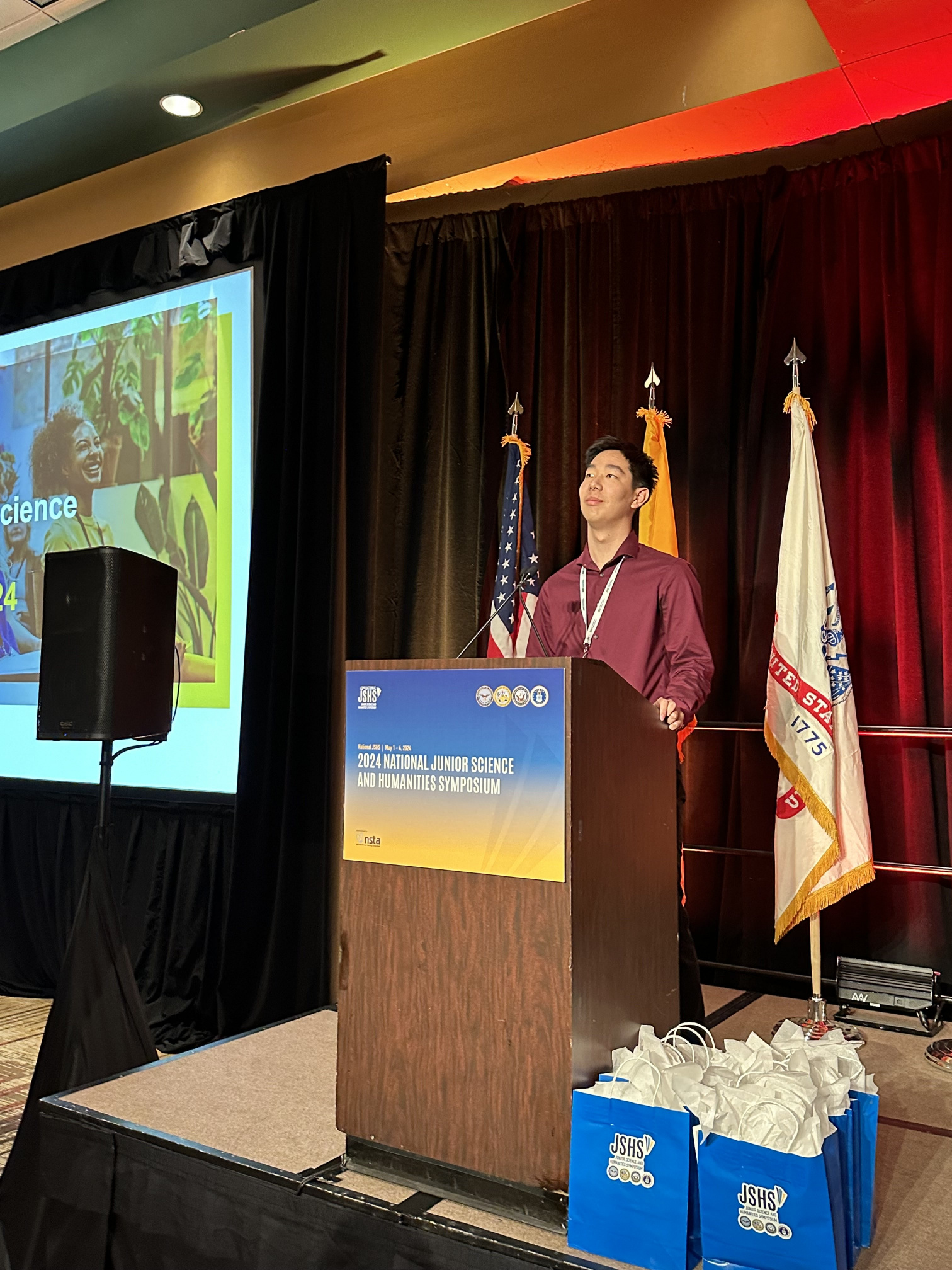 Alan presenting at the podium of the 2024 National Junior Science and Humanities Symposium