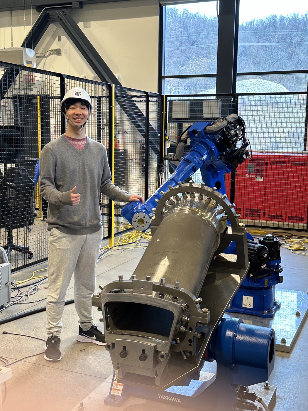 Alan in a hard hat next to a large blue Yaskawa industrial robot at Mill 19